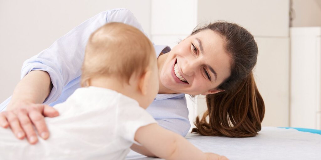 Sanfte Baby-Osteopathie: Osteopathin legt die Hand an einen Säugling in Bauchlage